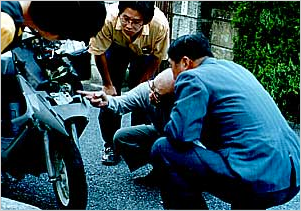 事故鑑定人の権威、駒沢鑑定士(右から2番目)の立ち会いの下、バイクについた傷を検証。どんな細かい傷も逃さない鋭い観察力に舌を巻いた。